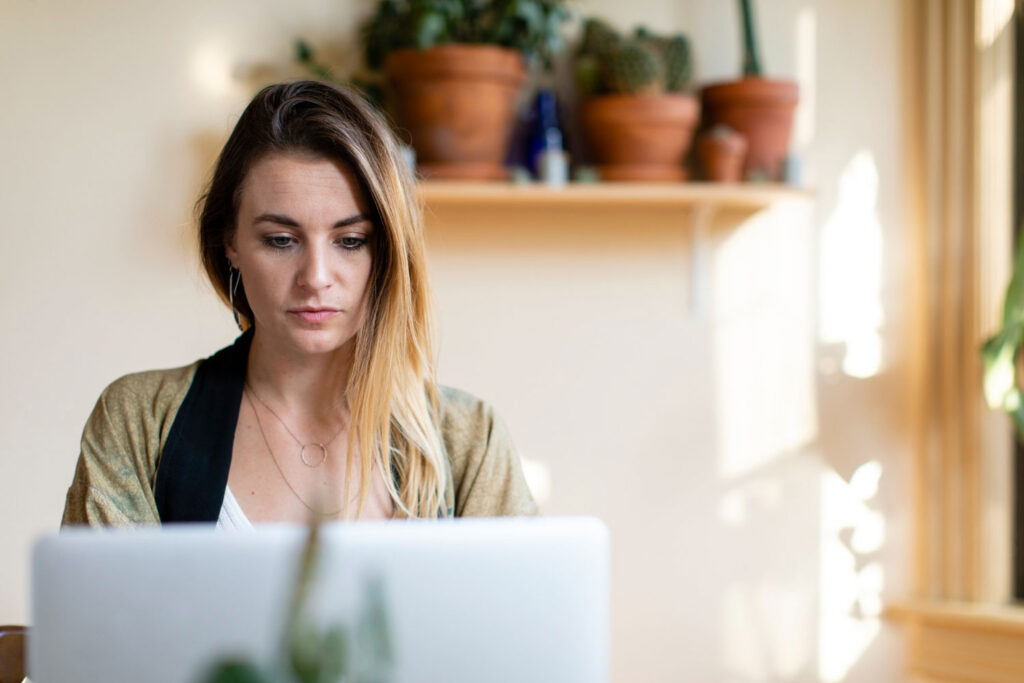 woman wearing golden kimono seating in front of a laptop with blurry background